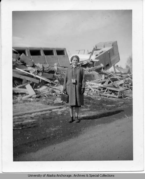 A woman stands in front of the wreckage of an apartment building in Anchorage.